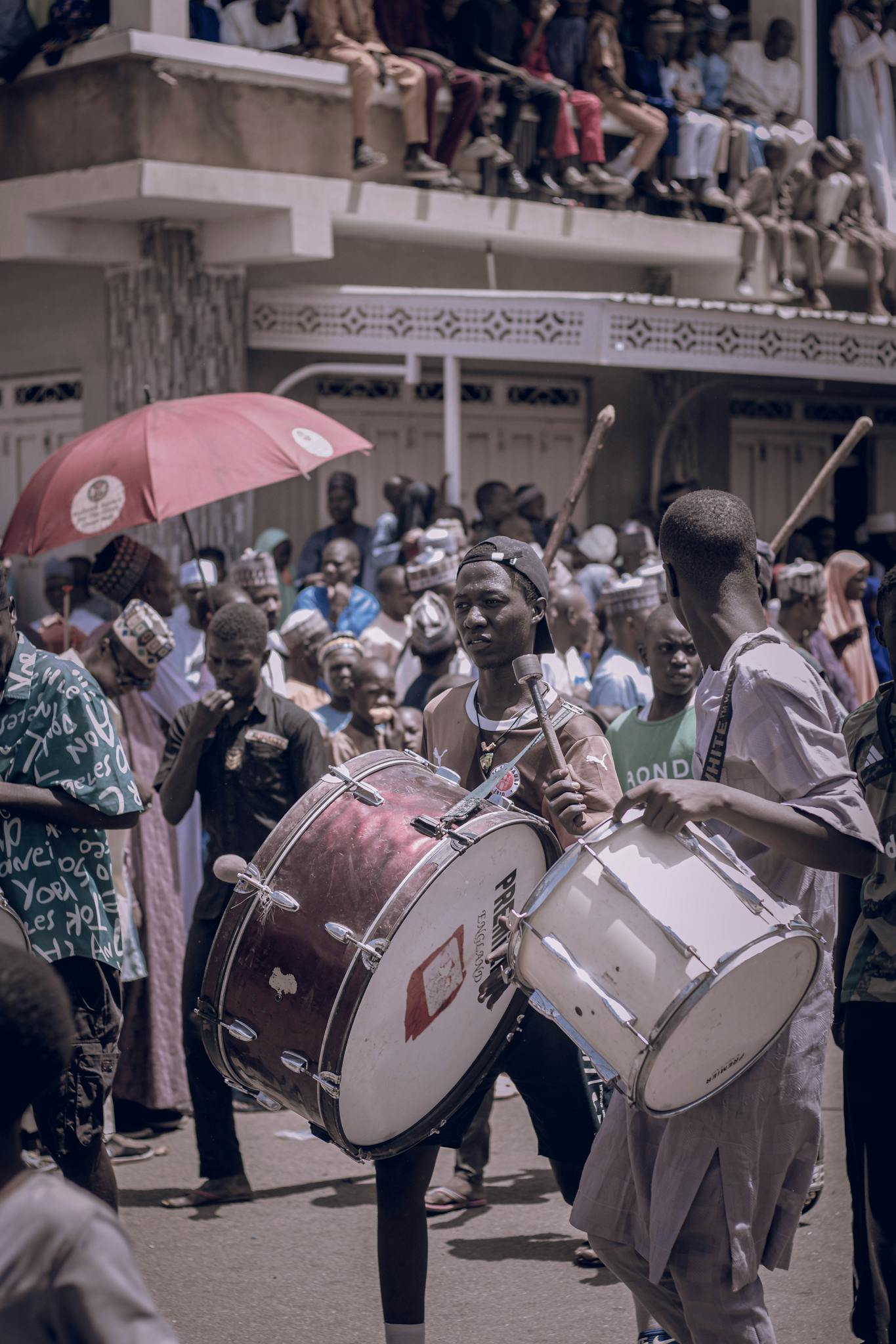 A lively street parade with drummers and onlookers engaging in cultural celebration.