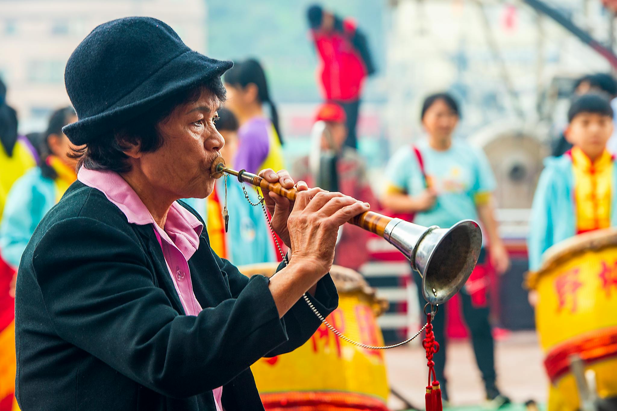 An adult musician playing a traditional wind instrument in a vibrant street performance in New Taipei City, Taiwan.